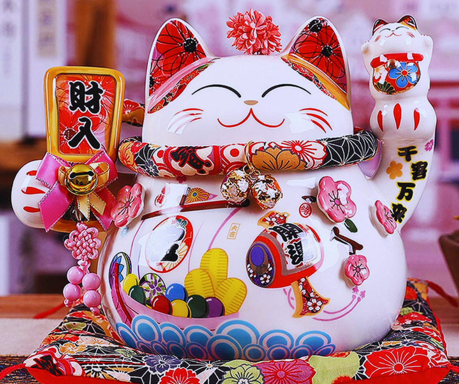 Outra característica interessante do Maneki-neko são os objetos que ele segura. A maioria das figuras traz uma moeda oval, conhecida como koban, que era usada no período Edo e simboliza riqueza. Em muitas versões, a moeda tem gravado o valor de 10 milhões de ryo, que representaria uma imensa fortuna.